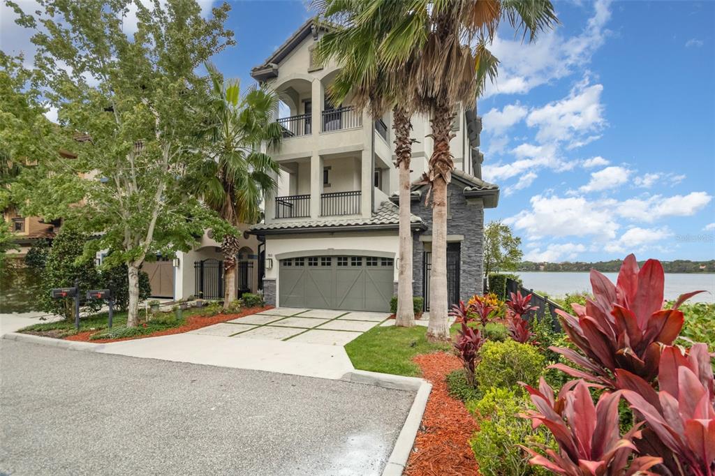 A three-story townhouse with a two-car garage and balconies overlooking a lake — 7601 TOSCANA BOULEVARD, ORLANDO, FL