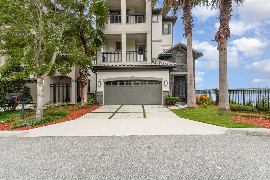A three-story house with a two-car garage, balconies, and a waterfront view — 7601 TOSCANA BOULEVARD, ORLANDO, FL