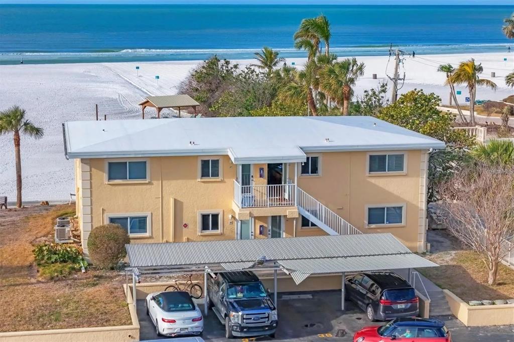An aerial view of a two-story yellow apartment building located next to a sandy beach — 6006 MIDNIGHT PASS ROAD UNIT 36, SARASOTA, FL