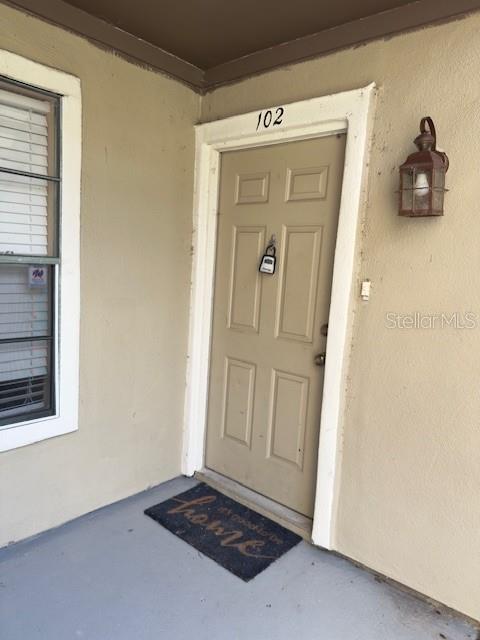 A tan exterior door numbered 102 features a lockbox and a welcome mat — 200 AFTON SQUARE UNIT 11-102, ALTAMONTE SPRINGS, FL