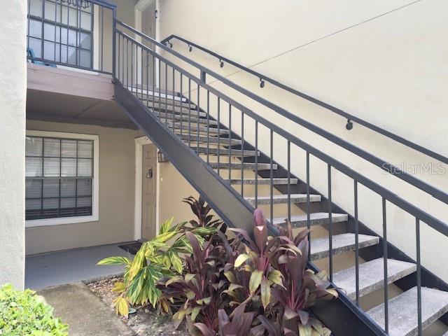 An outdoor staircase with black metal railings leads to the second-floor entrance of a building — 200 AFTON SQUARE UNIT 11-102, ALTAMONTE SPRINGS, FL