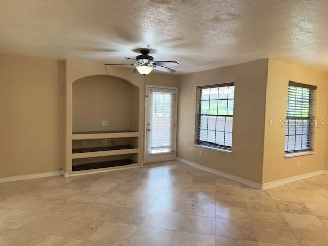 A living room features beige walls, tile flooring, a ceiling fan, and a built-in shelf — 200 AFTON SQUARE UNIT 11-102, ALTAMONTE SPRINGS, FL