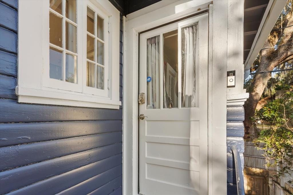 A white door with a glass pane sits next to a window on a blue-sided house — 1209 S MYRTLE AVENUE, SANFORD, FL