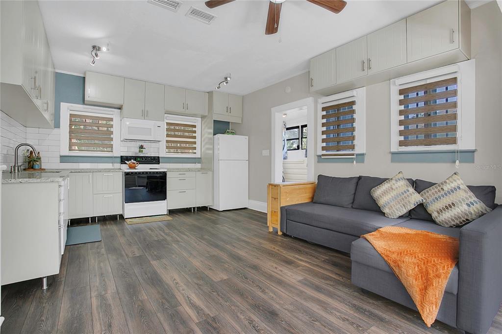 A kitchen and living area featuring light cabinetry, dark wood-look flooring, and a gray sofa — 1209 S MYRTLE AVENUE, SANFORD, FL