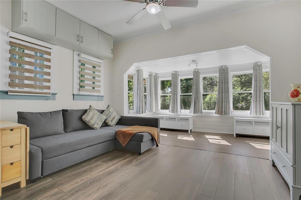 A living room with a gray sectional sofa, light wood floors, and a sunlit bay window — 1209 S MYRTLE AVENUE, SANFORD, FL