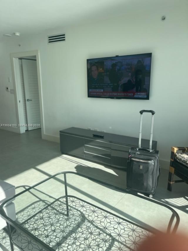 A living room features a wall-mounted television, a gray media console, and a rolling suitcase — 90 ALTON RD # 2908, Miami Beach FL 33139, MIAMI BEACH, FL