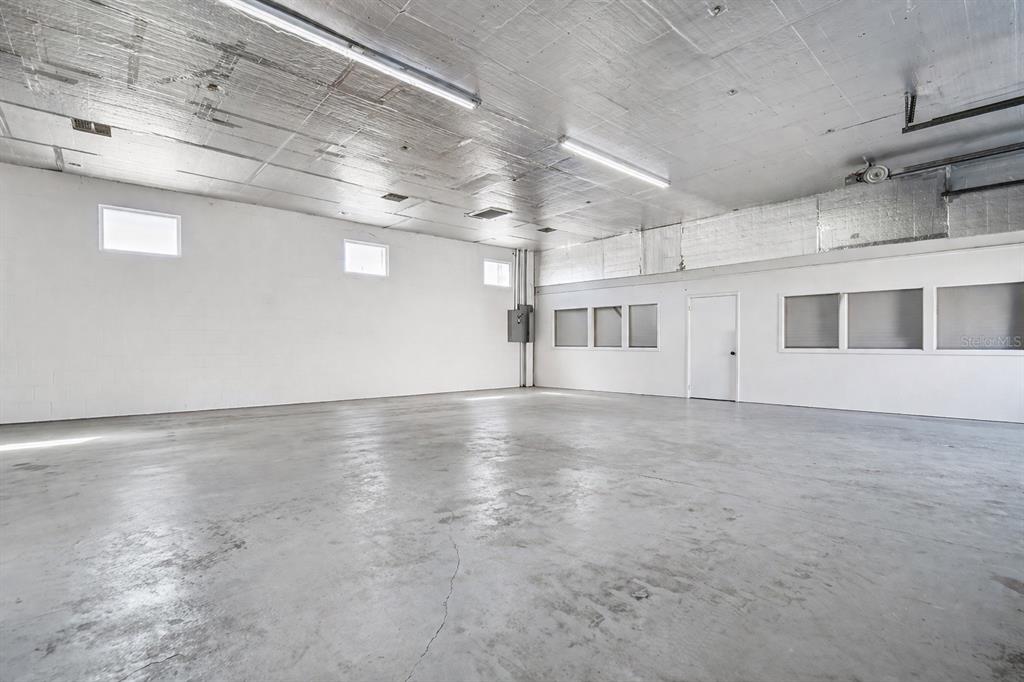 An empty industrial-style room features white block walls, a concrete floor, and reflective ceiling insulation — 6010 WALL STREET, PORT RICHEY, FL