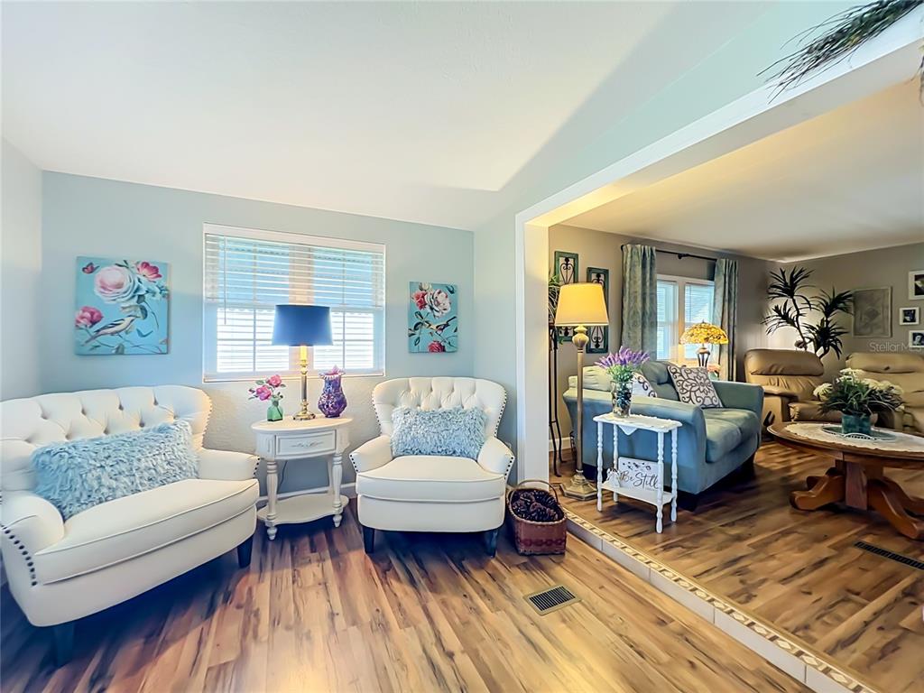 A living room with two white tufted chairs and a blue sofa in the background — 1108 NASSAU CIRCLE, TAVARES, FL