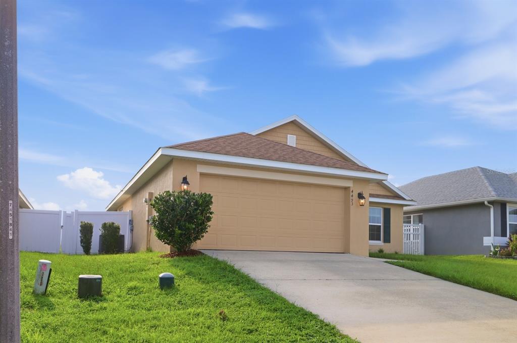 A tan single-story house with a two-car garage and a concrete driveway — 4493 NW 2ND COURT, OCALA, FL