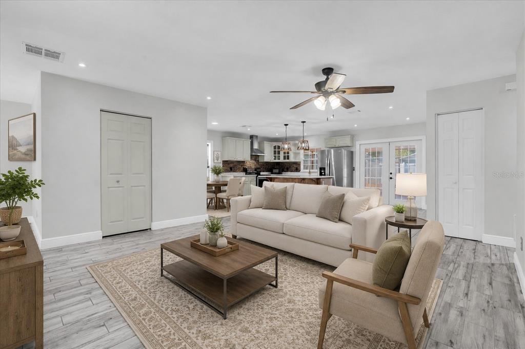 An open-concept living room features light gray walls, wood-look tile flooring, and a modern kitchen — 6832 SWAIN AVENUE, TAMPA, FL
