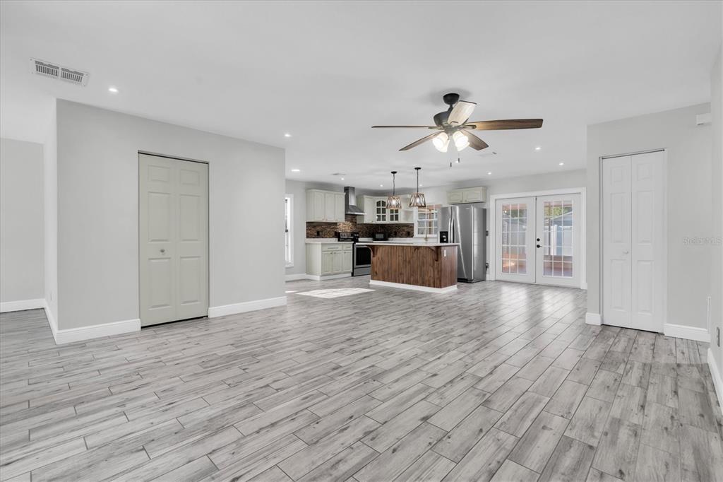 An open-concept kitchen and living area features light gray walls, wood-look tile flooring, and cabinetry — 6832 SWAIN AVENUE, TAMPA, FL