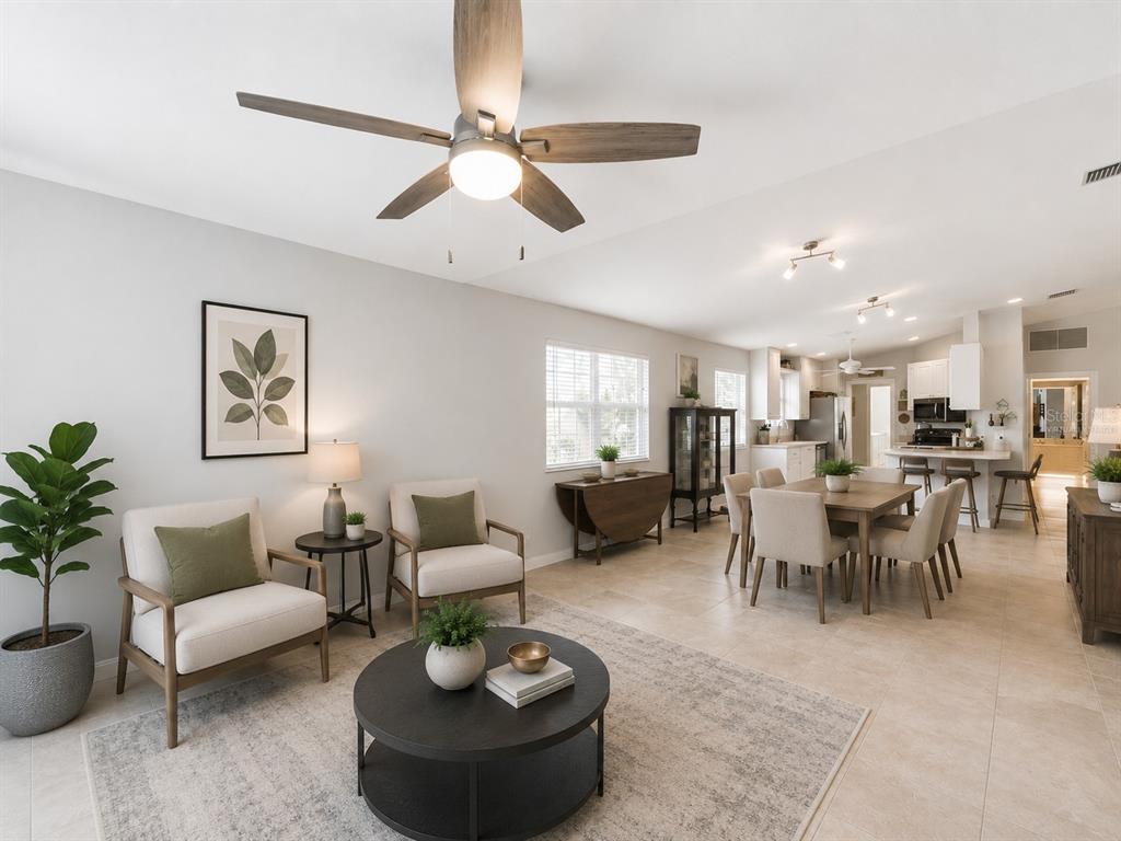 An open-concept living and dining area features tile flooring, a ceiling fan, and neutral decor — 11844 ASTILBE DRIVE, ORLANDO, FL