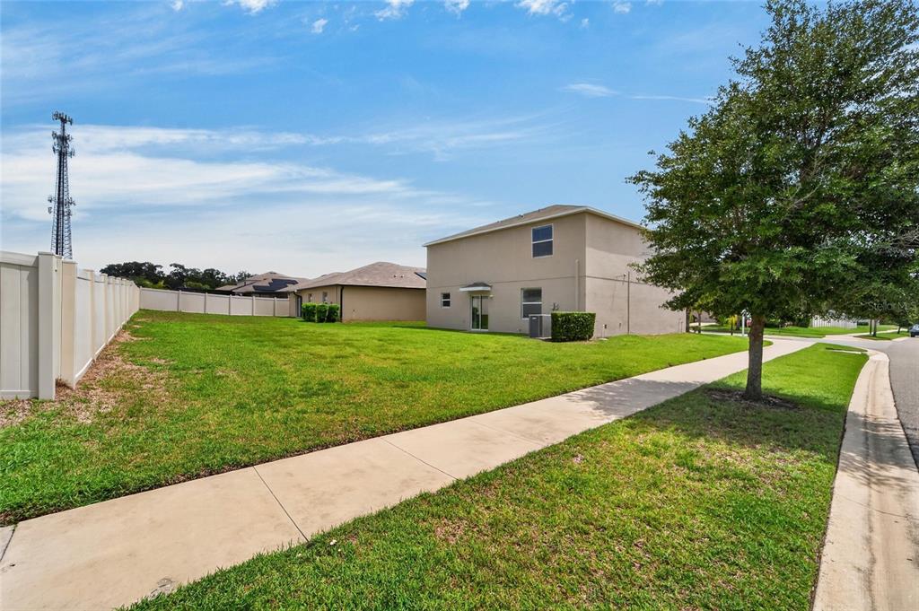 A side view of a two-story house with a large grassy yard and white fence — 215 ENGLISH HERITAGE PLACE, DOVER, FL
