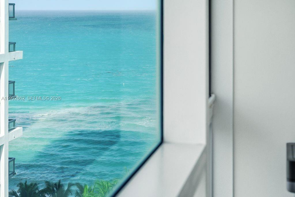 A view of the ocean through a large window in a white-walled room — 6801 Collins Ave # 1414, Miami Beach FL 33141, MIAMI BEACH, FL