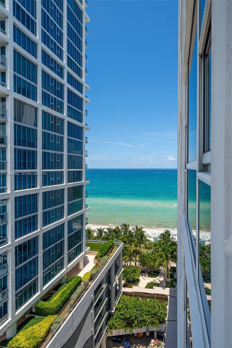 An elevated view shows a beach and ocean framed by two modern high-rise buildings — 6801 Collins Ave # 1414, Miami Beach FL 33141, MIAMI BEACH, FL