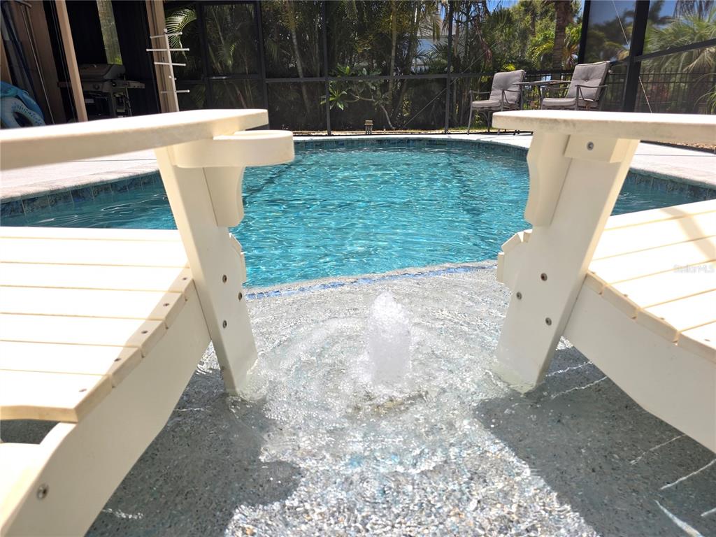 Two white chairs sit in a shallow pool ledge with a small water fountain — 95 SPORTSMAN ROAD, ROTONDA WEST, FL