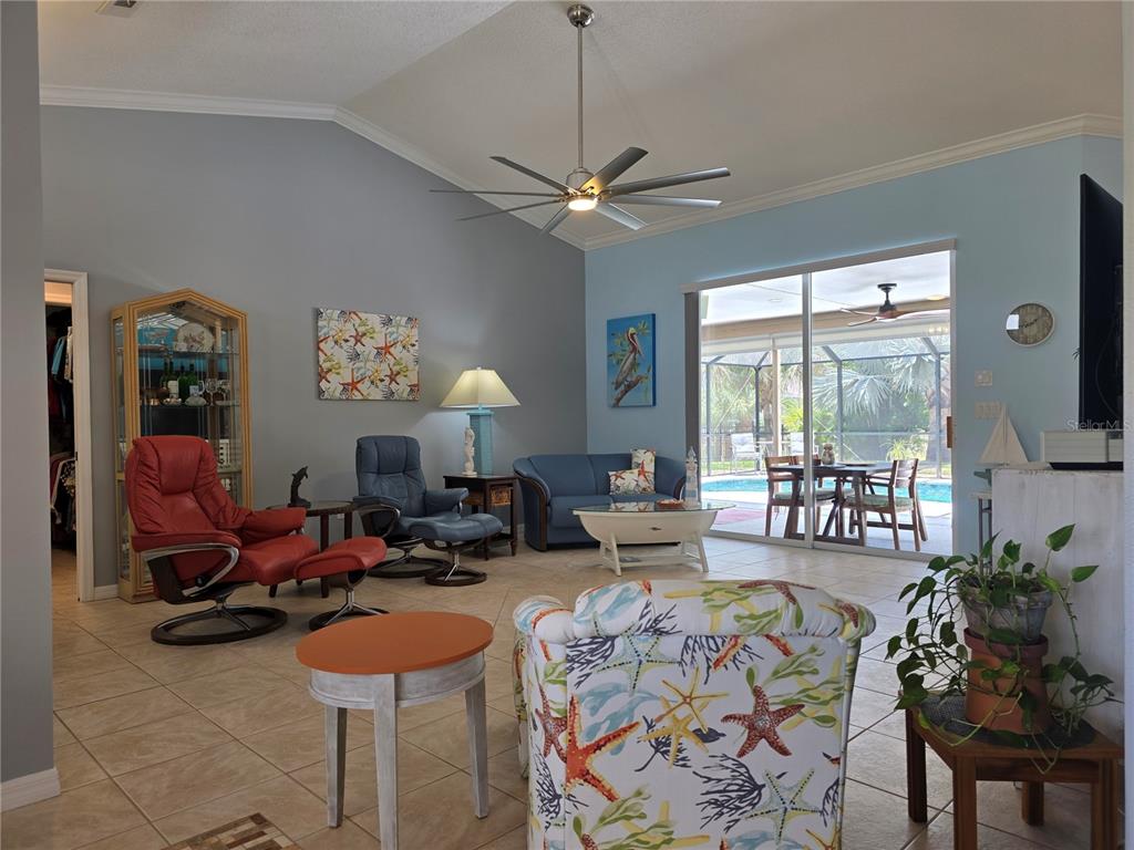 A living room features a vaulted ceiling, tile floors, and a sliding door to a pool — 95 SPORTSMAN ROAD, ROTONDA WEST, FL