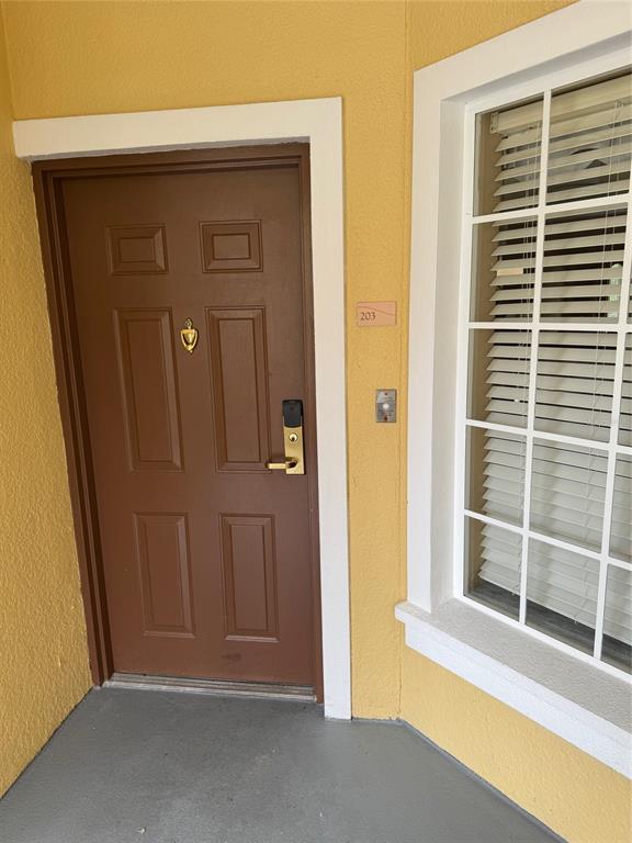 A brown front door with a gold knocker and electronic lock next to a window — 8762 WORLDQUEST BOULEVARD UNIT 6203, ORLANDO, FL