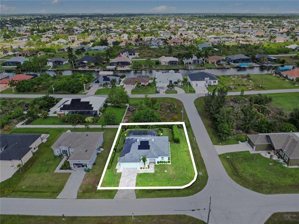 An aerial view shows a single-story house with a pool cage on a corner lot — 9241 KING HILL STREET, PORT CHARLOTTE, FL