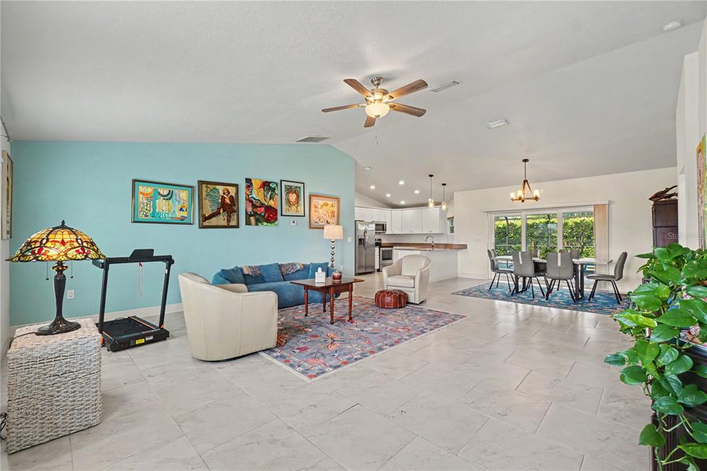 An open-concept living and dining area features light blue walls, tile flooring, and a kitchen — 9241 KING HILL STREET, PORT CHARLOTTE, FL