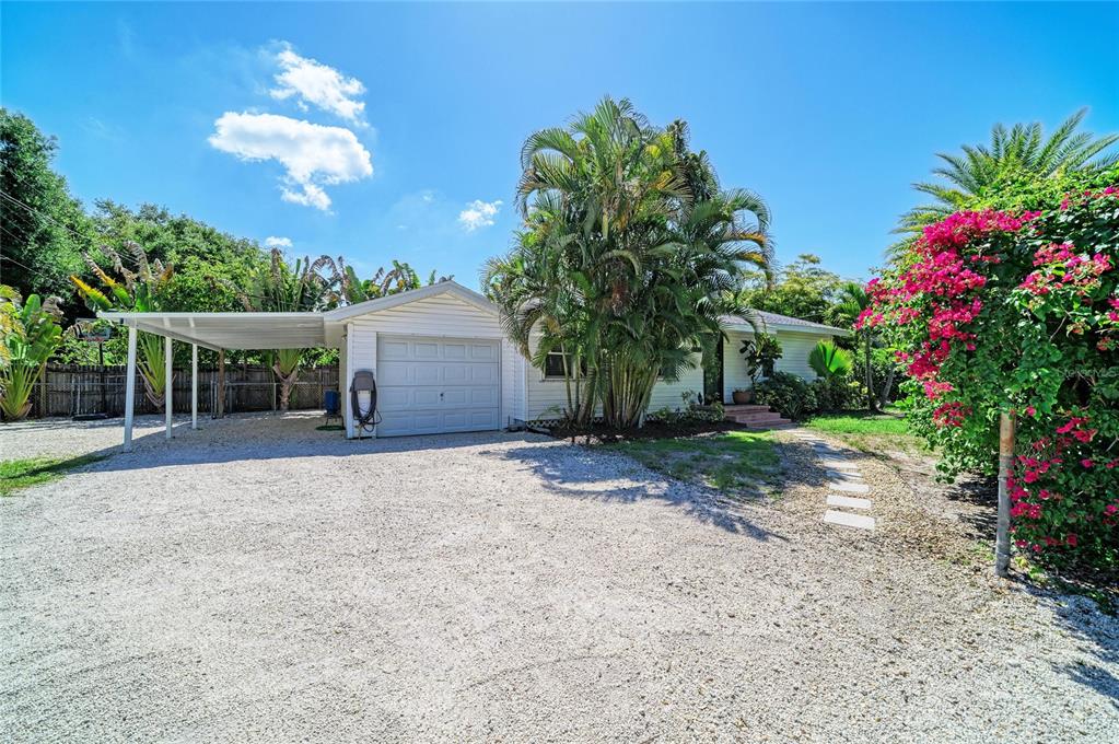A single-story house with a gravel driveway, a carport, and a large palm tree — 3710 RILMA AVENUE, SARASOTA, FL