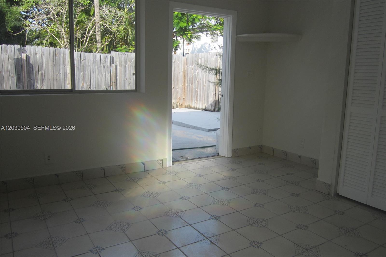 An interior room features white tile flooring, a window, and an open door to a patio — HOLLYWOOD, FL