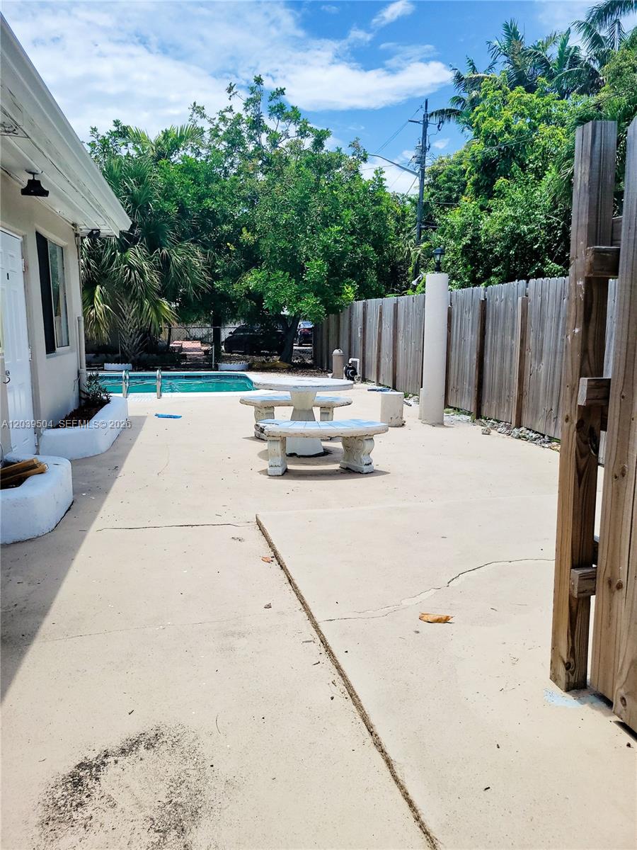 A concrete patio features a stone table and benches beside a swimming pool — HOLLYWOOD, FL
