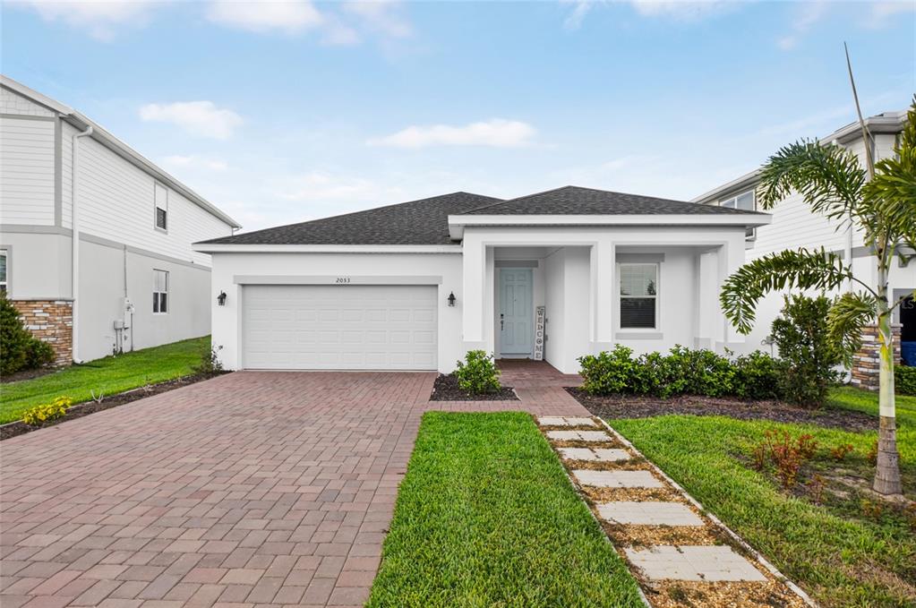 A single-story house with a white exterior, a two-car garage, and a paved driveway — 2053 HEART LAKE DRIVE, GROVELAND, FL