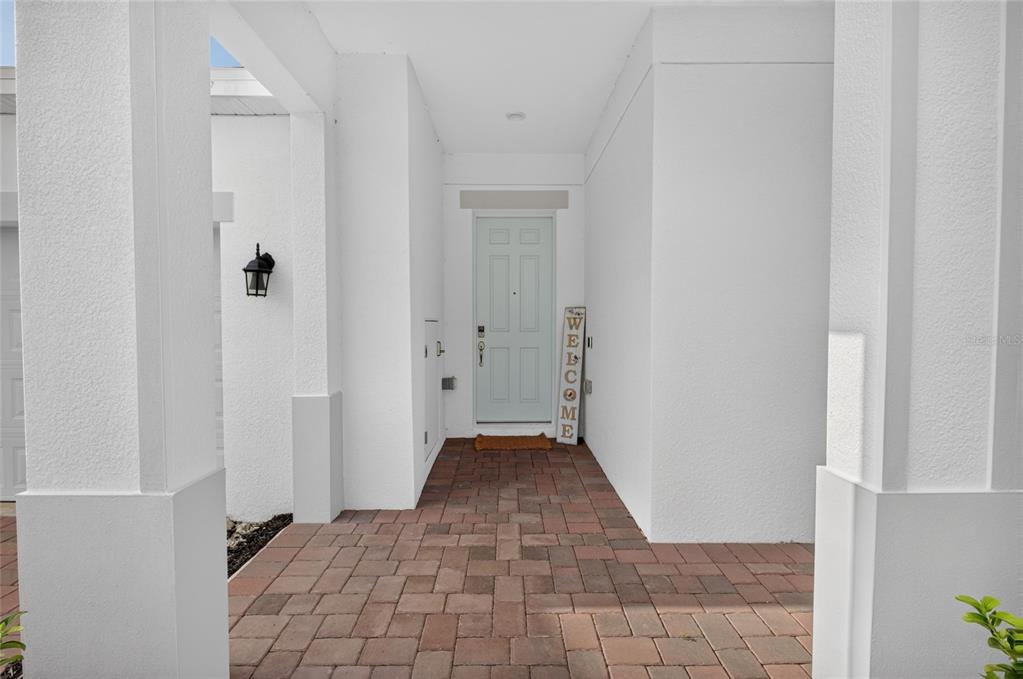A covered entryway features a brick-paved floor, white columns, and a light blue front door — 2053 HEART LAKE DRIVE, GROVELAND, FL