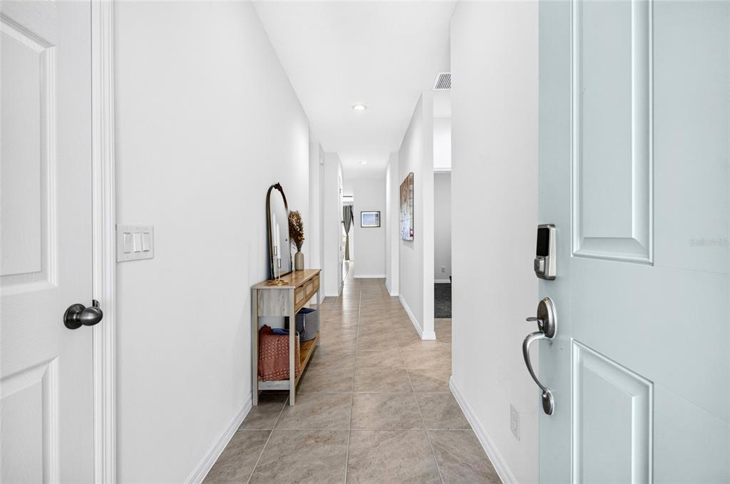A bright entryway leads into a long hallway with tile flooring and a console table — 2053 HEART LAKE DRIVE, GROVELAND, FL