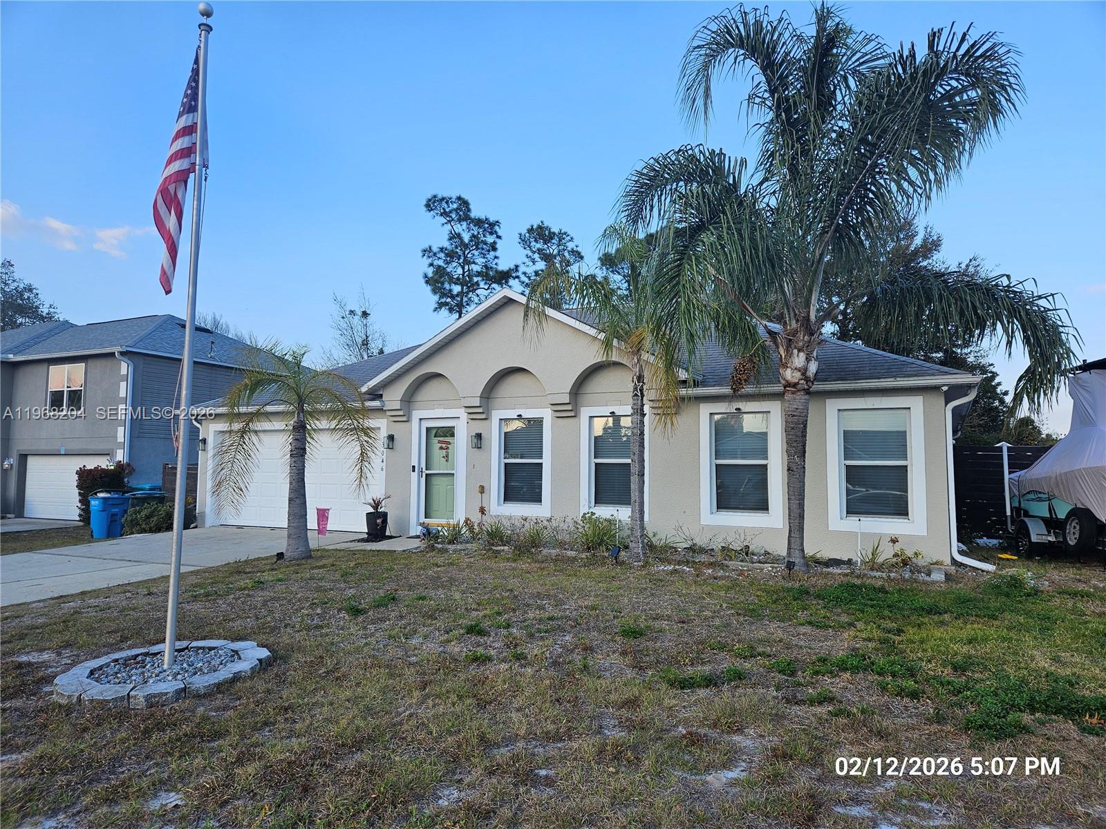 A single-story house with a flag pole, palm trees, and a two-car garage — 3046 Blaine Cir, Deltona FL 32738, DELTONA, FL