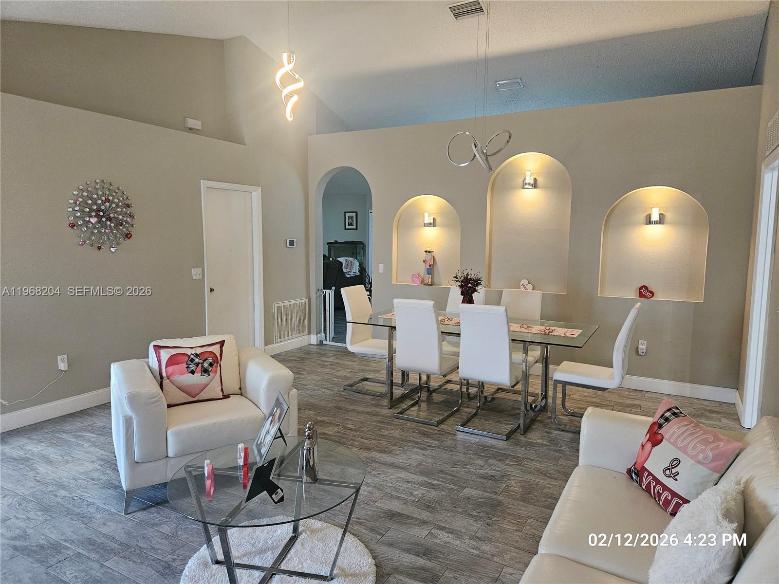 A living and dining area features white furniture, arched wall niches, and wood-look tile flooring — 3046 Blaine Cir, Deltona FL 32738, DELTONA, FL