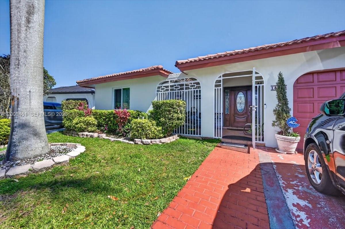 The exterior of a single-story house features a red brick walkway and a gated entrance — 14313 SW 100th Ln, Miami FL 33186, MIAMI, FL