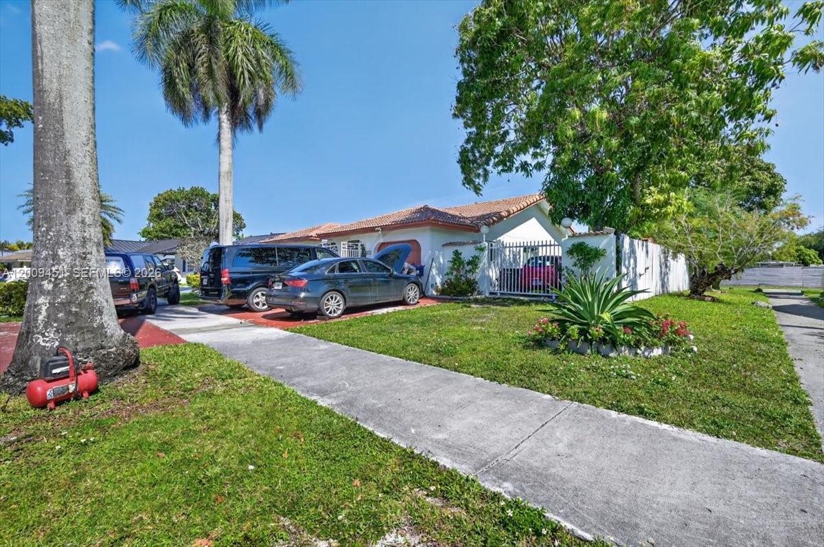 A single-story house with a driveway, palm tree, and parked vehicles under a blue sky — 14313 SW 100th Ln, Miami FL 33186, MIAMI, FL