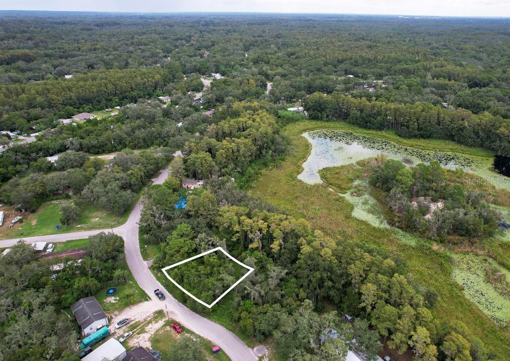 An aerial view shows a vacant, wooded lot outlined in white next to a small lake — 33 POPLAR STREET, NEW PORT RICHEY, FL