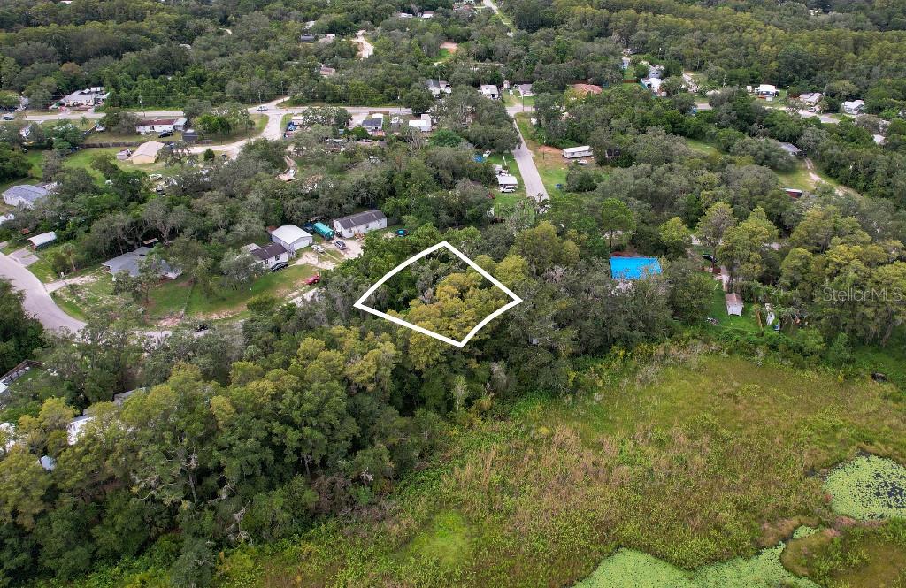 An aerial view shows a wooded lot outlined in white near a grassy marsh area — 33 POPLAR STREET, NEW PORT RICHEY, FL