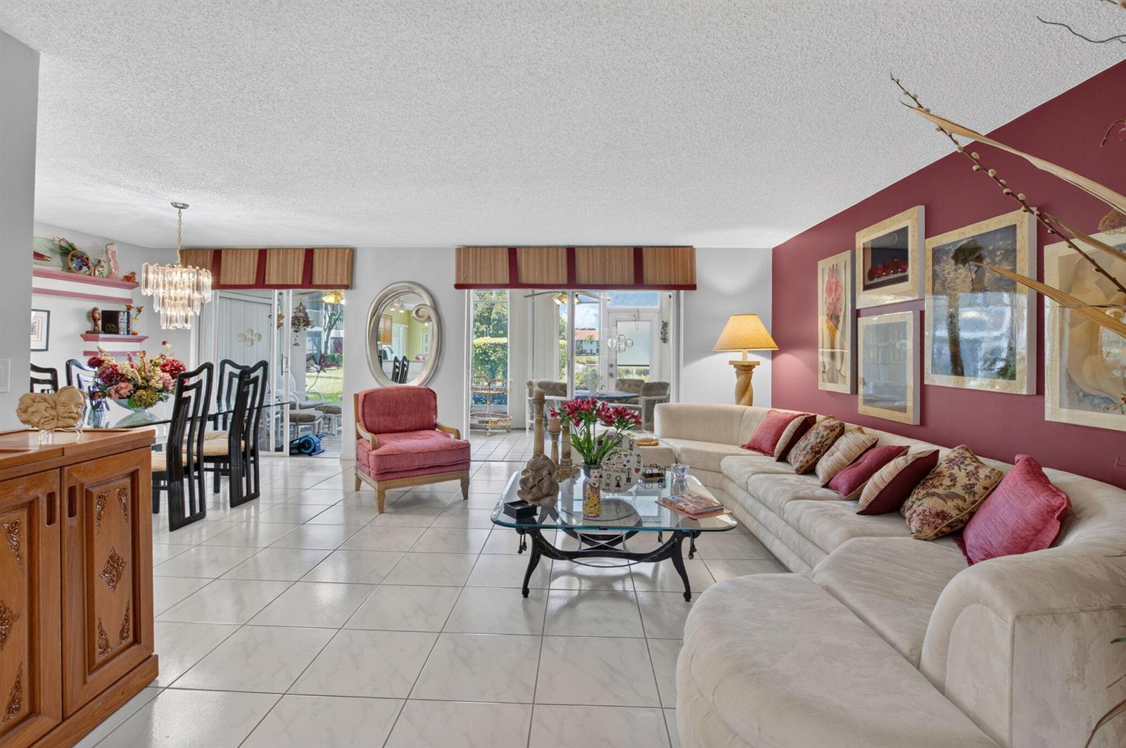 A living and dining area features white tile floors, a red accent wall, and sliding doors — 7825 Whispering Palms Drive # 101, Boynton Beach FL 33437, BOYNTON BEACH, FL