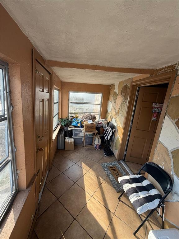 A sunroom with tile flooring, a stone-patterned wall, and a door leading to another room — 3908 E GENESEE STREET, TAMPA, FL