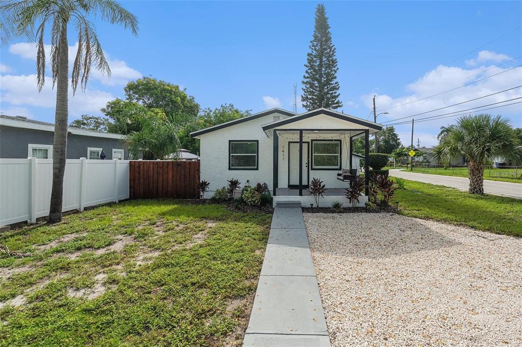 A single-story white house with a covered front porch and a gravel driveway — 1411 S MADISON AVENUE, CLEARWATER, FL