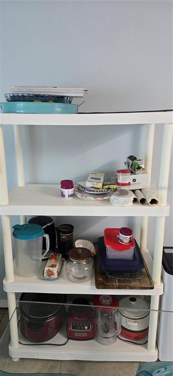 A white four-tier plastic shelving unit holds various kitchen appliances, containers, and household items — 3700 S ATLANTIC AVENUE UNIT 205, NEW SMYRNA BEACH, FL