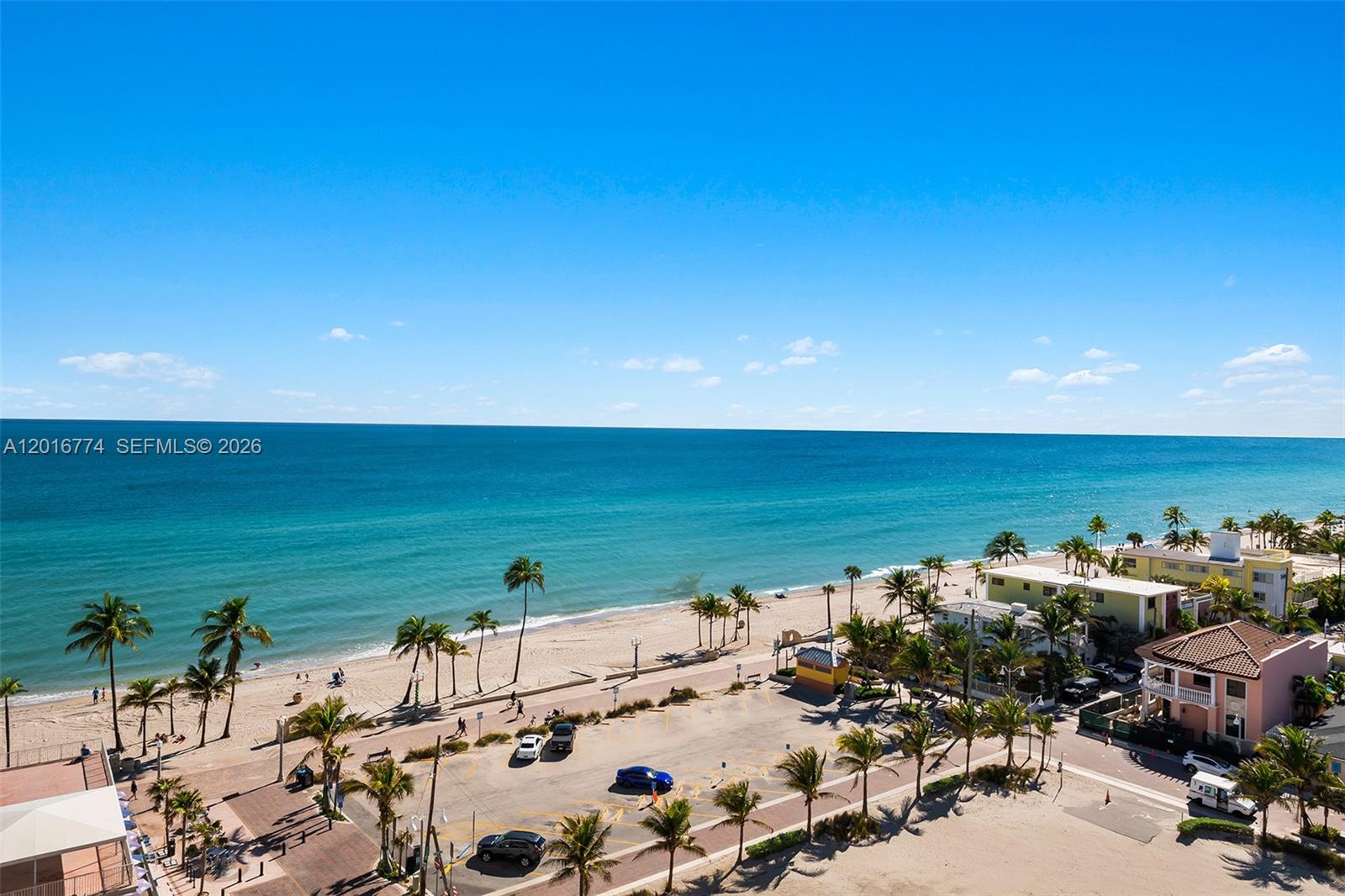 An elevated view shows a sandy beach, ocean, and parking area with palm trees — 3111 N Ocean Dr # 1110, Hollywood FL 33019, HOLLYWOOD, FL