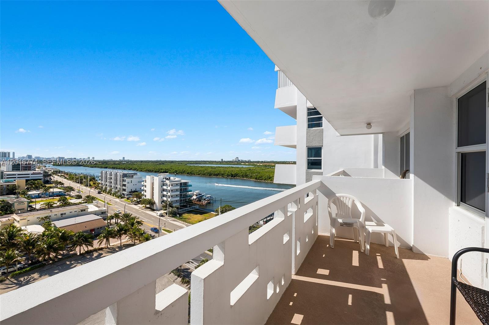 A balcony with white railings overlooks a waterway, a road, and surrounding buildings — 3111 N Ocean Dr # 1110, Hollywood FL 33019, HOLLYWOOD, FL