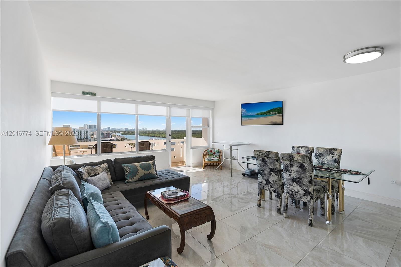 A living and dining area features tile floors, a sectional sofa, and a balcony view — 3111 N Ocean Dr # 1110, Hollywood FL 33019, HOLLYWOOD, FL