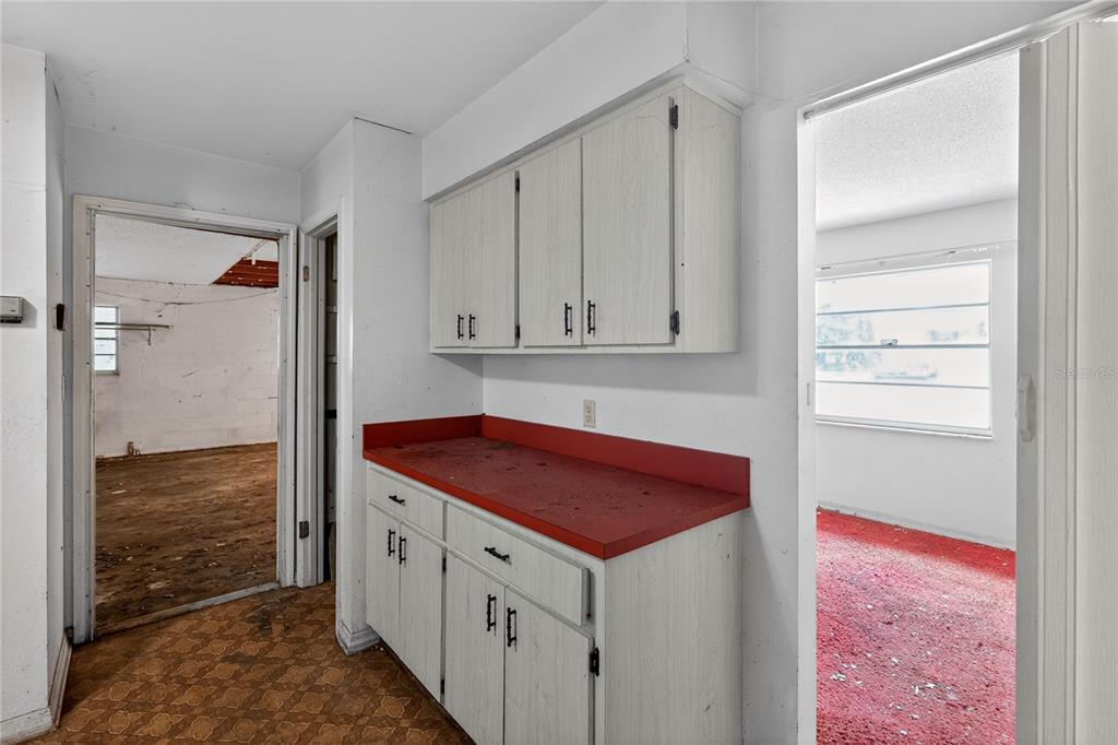 A kitchen area features white cabinets, a red countertop, and doorways leading to other rooms — 320 LAKE MILLSITE ROAD, BARTOW, FL