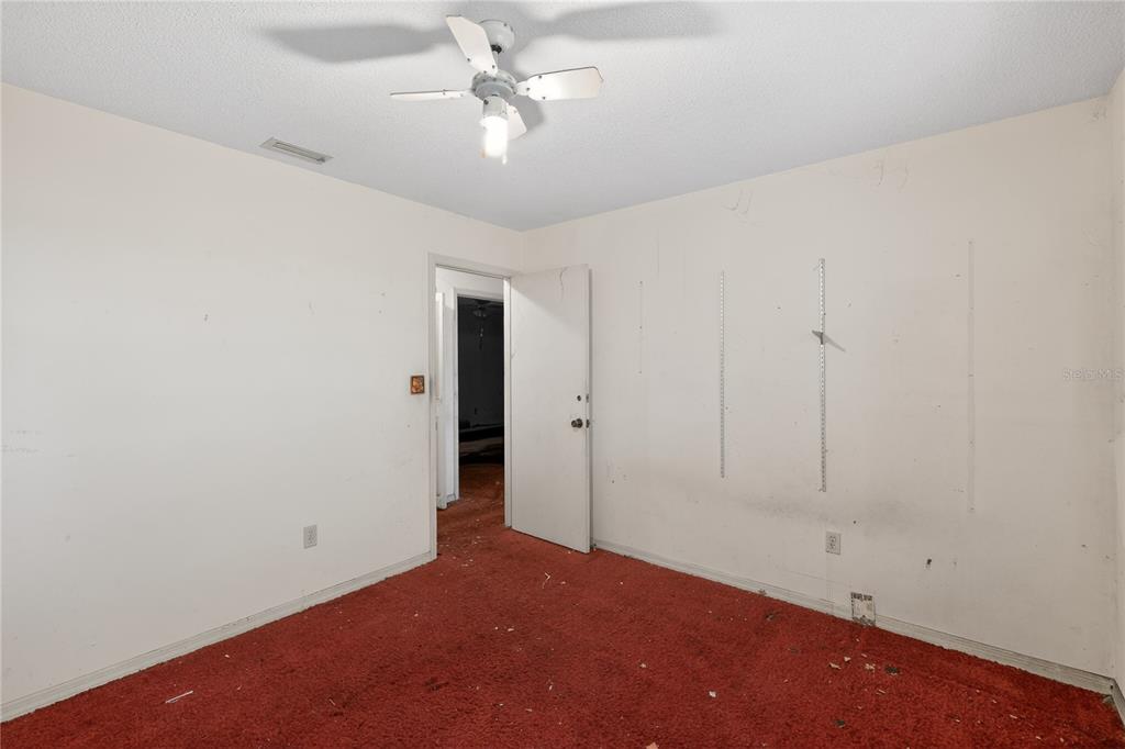 An empty bedroom features red carpeting, white walls, and a ceiling fan — 320 LAKE MILLSITE ROAD, BARTOW, FL