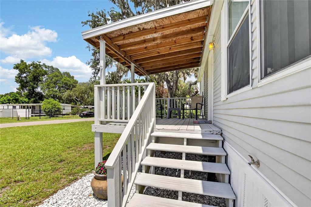 An exterior view of a mobile home featuring a wooden porch and white stairs — 38310 PEAR COURT, ZEPHYRHILLS, FL