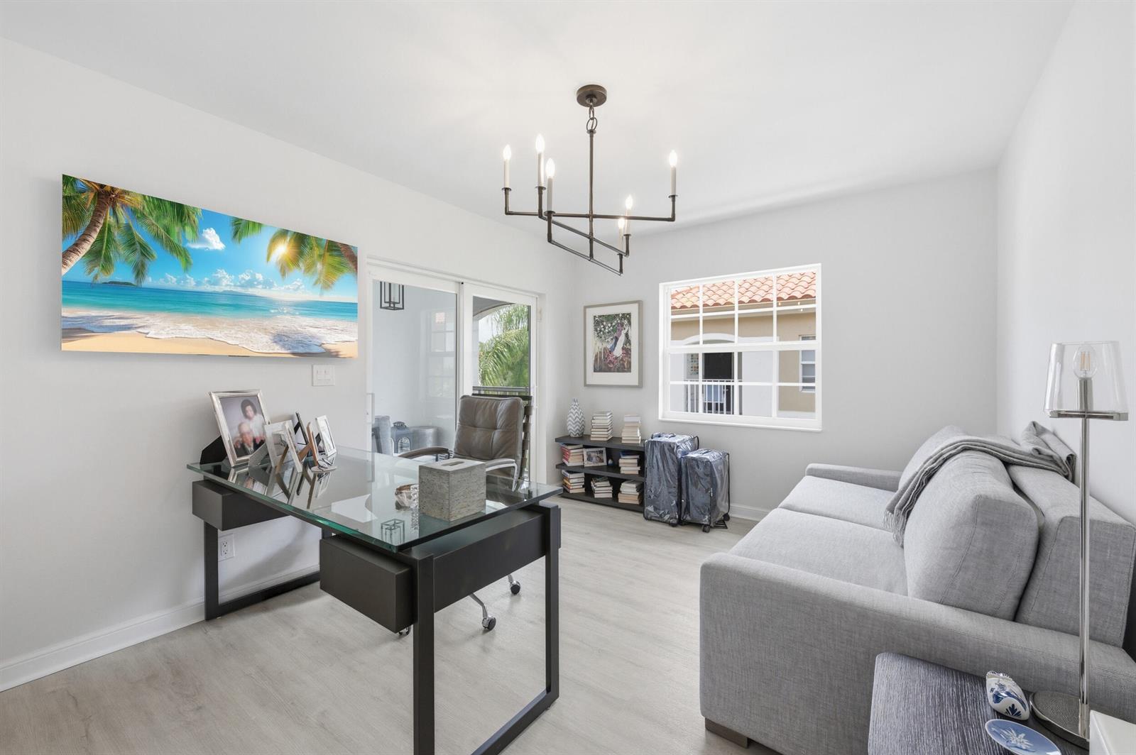 A home office features a glass desk, a gray sofa, and a beach-themed wall art piece — 7369 Orangewood Lane, Boca Raton FL 33433, BOCA RATON, FL