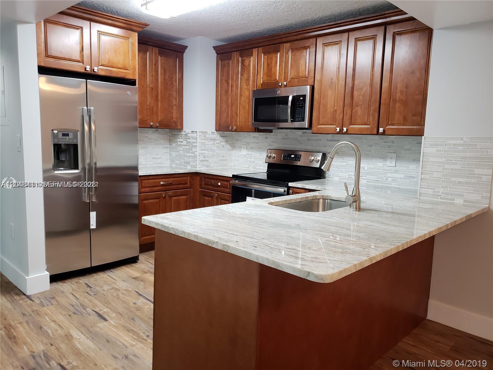 A kitchen features wood cabinets, stainless steel appliances, a stone countertop, and a tile backsplash — 104 SW 9th St # 304, Miami FL 33130, MIAMI, FL
