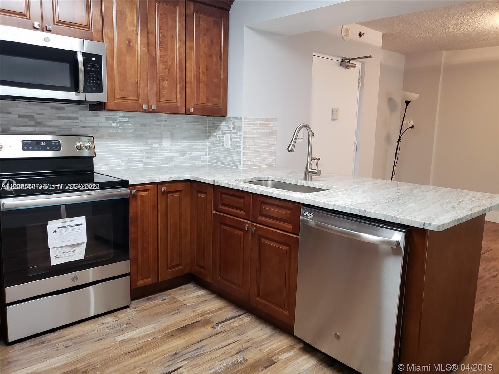 A kitchen features wood cabinets, stainless steel appliances, and light-colored stone countertops — 104 SW 9th St # 304, Miami FL 33130, MIAMI, FL