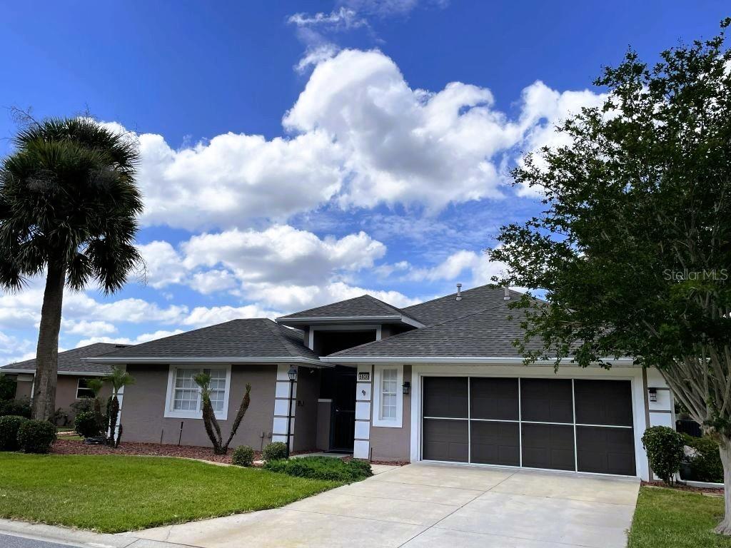 A single-story house with a gray exterior, a two-car garage, and a palm tree — 5920 BAG PIPE PLACE, LEESBURG, FL